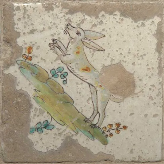 Azulejo del pavimento con una liebre pintada saltando sobre unas matas